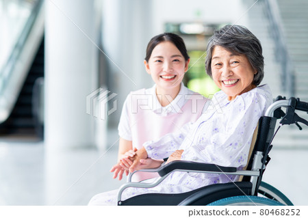 Elderly and caregiving young woman in wheelchair 80468252