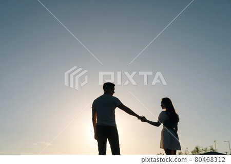 Silhouette of loving young couple dancing at sunset on background of cloudless sky in evening. 80468312