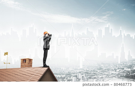 Engineer man standing on roof and looking in binoculars. Mixed m 80468773
