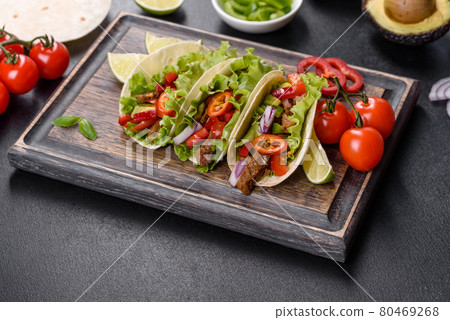 Mexican tacos with beef, tomatoes, avocado, onion and salsa sauce 80469268