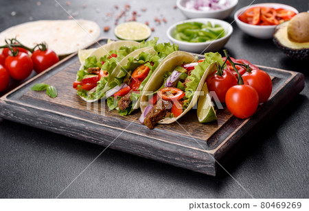 Mexican tacos with beef, tomatoes, avocado, onion and salsa sauce 80469269