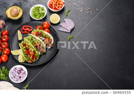 Mexican tacos with beef, tomatoes, avocado, onion and salsa sauce on a dark concrete background 80469350