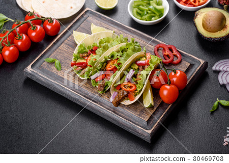 Mexican tacos with beef, tomatoes, avocado, onion and salsa sauce on a dark concrete background Mexican tacos with beef, tomatoes, avocado, onion and salsa sauce on a dark concrete background 80469708
