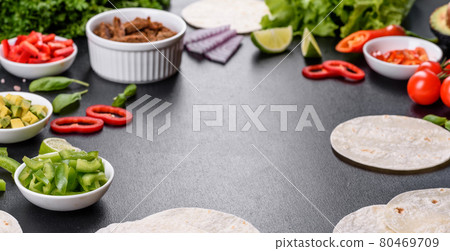 Mexican tacos with beef, tomatoes, avocado, onion and salsa sauce on a dark concrete background Mexican tacos with beef, tomatoes, avocado, onion and salsa sauce on a dark concrete background 80469709