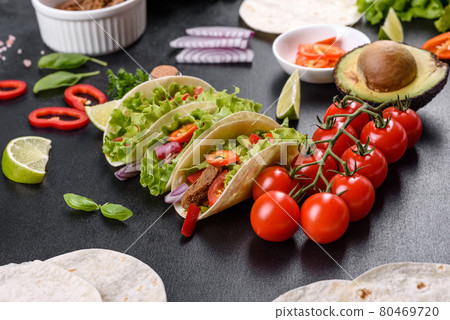 Mexican tacos with beef, tomatoes, avocado, onion and salsa sauce 80469720