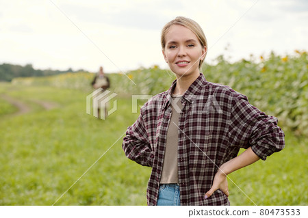 Young blond smiling female farmer in workwear using tablet against green field Young blond smiling female farmer in workwear using tablet against green field 80473533