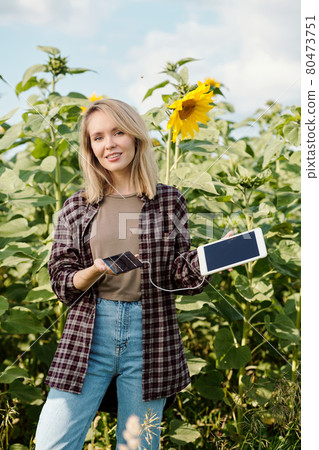 Happy young female holding digital tablet plugged to solar battery for charging 80473751