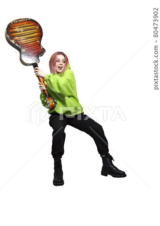 Crazy teen girl in a green hoodie wants to smash a guitar. Crazy teen girl in a green hoodie wants to smash a guitar. 80473902