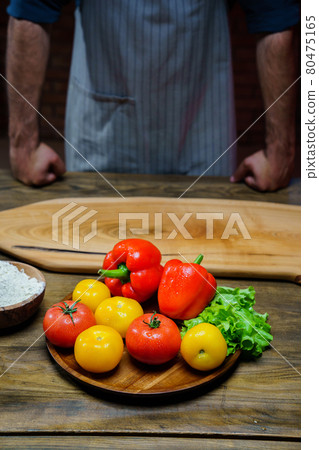 yellow and red tomatoes, lettuce and bell pepper with water drops. man in apron. yellow and red tomatoes, lettuce and bell pepper with water drops. man in apron. 80475165