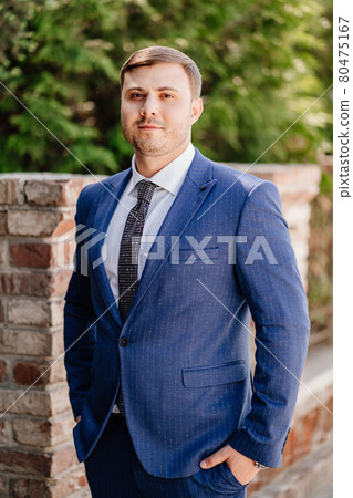 portrait of a man in a blue jacket near the brick fence portrait of a man in a blue jacket near the brick fence 80475167