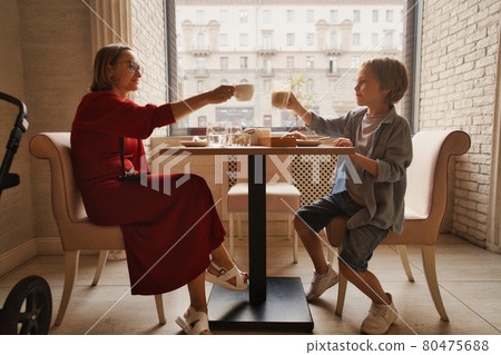 young mom having coffee with her son in street cafe 80475688