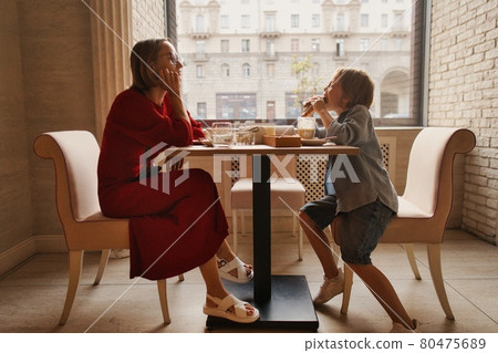 young mom having coffee with her son in street cafe young mom having coffee with her son in street cafe 80475689