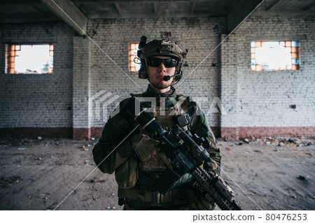 Close-up of a professional fully equipped soldier looking at camera. Close-up of a professional fully equipped soldier looking at camera. 80476253