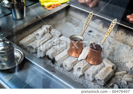 A turkish coffee pot on some wood burning with coffee inside. Street coffee in Istanbul, Turkey. A turkish coffee pot on some wood burning with coffee inside. Street coffee in Istanbul, Turkey. 80476407