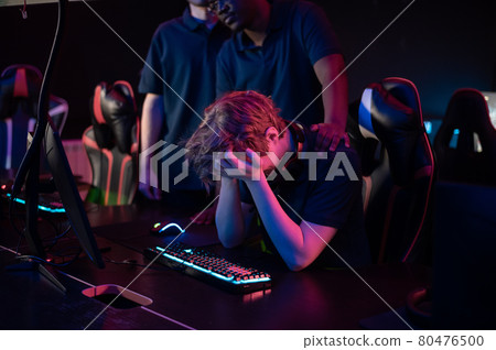 A cute guy is worried about losing a computer game, his friends calm him down 80476500