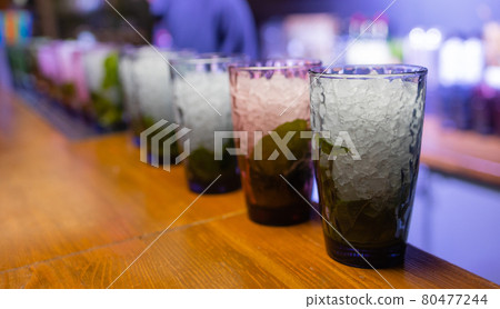 Bartender putting lime into glass. Muddling lime to make a cocktail. Barman holding glass. Bartender putting lime into glass. Muddling lime to make a cocktail. Barman holding glass. 80477244