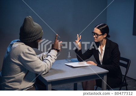 A black guy listens to his rights from a civil lawyer at a table in a visiting room in a state prison 80477312