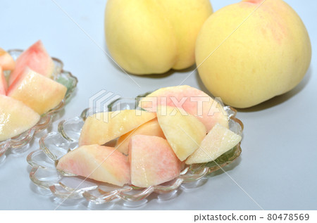 Cut white peach on glass tableware with white peach from Okayama in the background 80478569