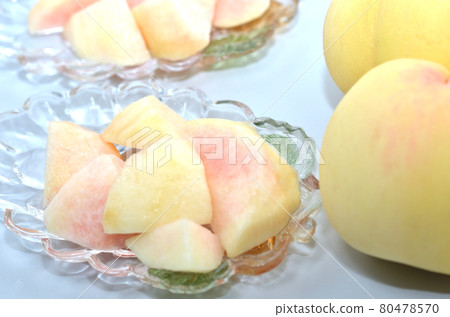 Cut white peach on glass tableware with white peach from Okayama in the background 80478570