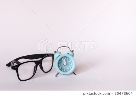 black glasses and a blue alarm clock shows 12 twelve o'clock. mock up black glasses and a blue alarm clock shows 12 twelve o'clock. mock up 80478604