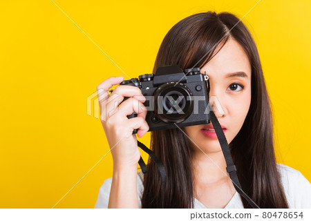 Woman photographer taking picture and looking viewfinder on digital mirrorless photo camera 80478654