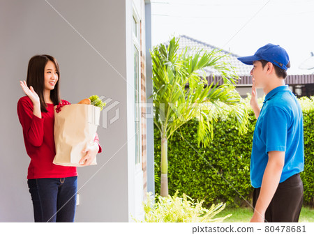 Delivery man making grocery service giving fresh vegetables in paper bag to woman customer 80478681