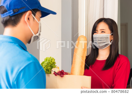 Delivery man wear protective face mask making grocery giving fresh food to woman customer 80478682