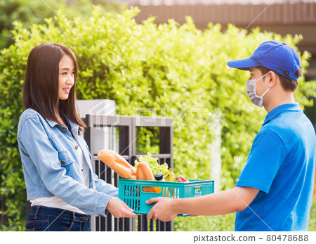 Delivery man wear face mask grocery fast service giving fresh food vegetable to woman customer Delivery man wear face mask grocery fast service giving fresh food vegetable to woman customer 80478688