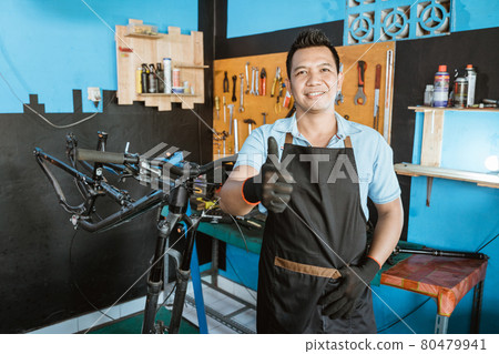Portrait of a handsome repairman with thumbs up in an apron Portrait of a handsome repairman with thumbs up in an apron 80479941