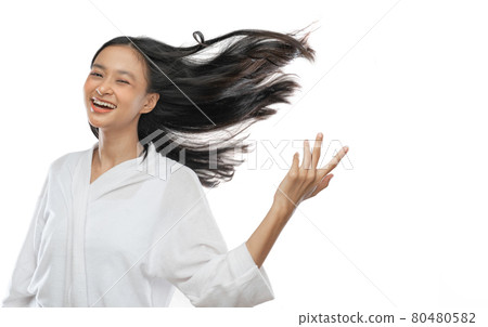 smiling asian girl wearing a towel is standing with her long black hair blowing by wind smiling asian girl wearing a towel is standing with her long black hair blowing by wind 80480582