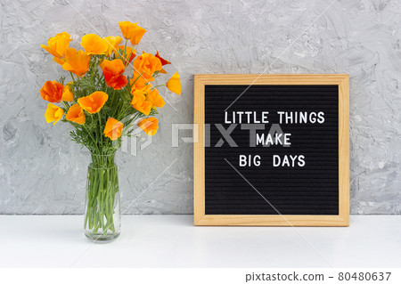 Little things make big days. Motivational quote on letter board and bouquet orange flowers on white table against grey stone wall. Concept inspirational quote of the day 80480637