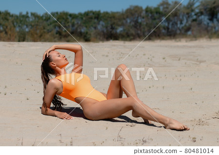 Attractive woman in sexy swimsuit relaxing on beach 80481014
