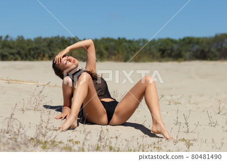 Sensual woman in black underwear relaxing on sandy beach 80481490