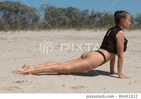 Graceful woman doing yoga pose on sandy beach 80481812