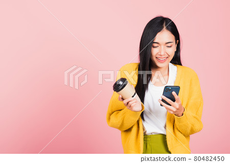 Happy Asian portrait beautiful cute young woman excited smiling holding mobile phone and coffee to go 80482450