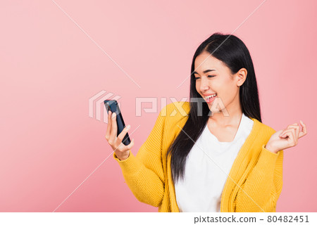 Happy Asian portrait beautiful cute young woman excited laughing holding mobile phone 80482451