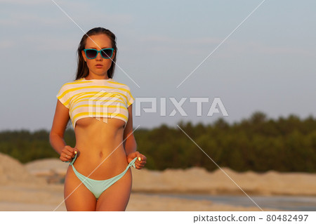 Sexy model in crop top and bikini panties on beach Sexy model in crop top and bikini panties on beach 80482497
