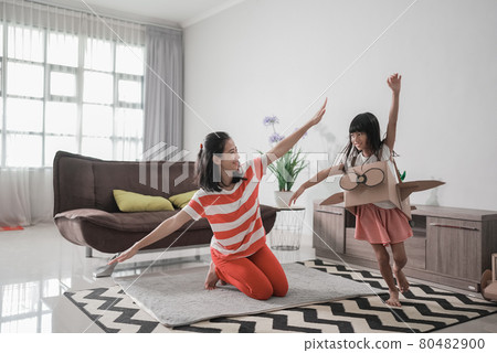 girl playing with cardboard toy airplane at home with mother girl playing with cardboard toy airplane at home with mother 80482900