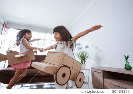 girl playing with cardboard toy airplane at home girl playing with cardboard toy airplane at home 80484551