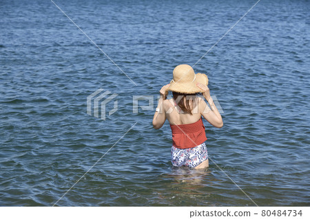 Taking a portrait of a woman in a swimsuit in a straw hat on the coast of Otobe-cho, Hokkaido in the summer 80484734