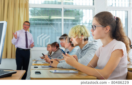 Side view of student group working with mobile phones in class Side view of student group working with mobile phones in class 80486229