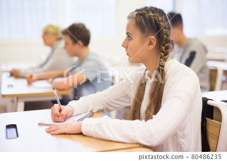 Teen girl sitting at desk in classroom Teen girl sitting at desk in classroom 80486235