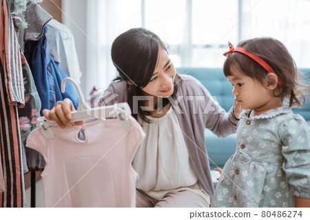 beautiful asian mother taking her daughter to buy clothes 80486274