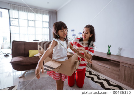 girl playing with cardboard toy airplane at home girl playing with cardboard toy airplane at home 80486350