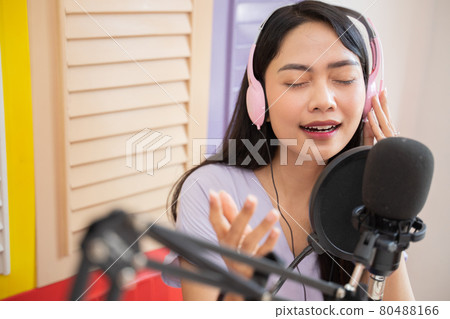 a beautiful singer wearing headphones with hand gestures while listening to a song a beautiful singer wearing headphones with hand gestures while listening to a song 80488166