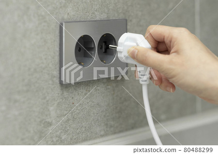 hand plugging out cord from outlet 80488299