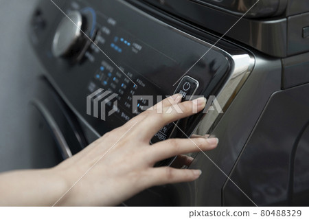Hand pressing the washing machine power switch 80488329