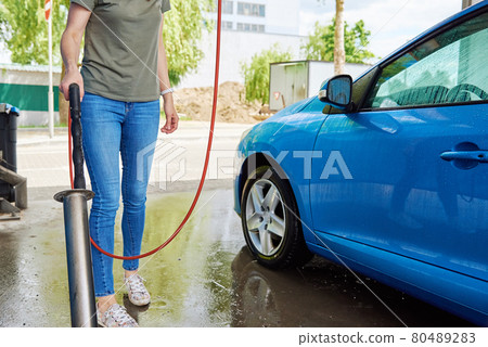 Cleaning car with high pressure water at car wash station 80489283