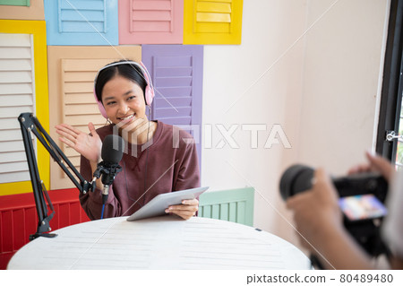 happy girl wearing headphones in front of microphone greeting gesture during podcast opening happy girl wearing headphones in front of microphone greeting gesture during podcast opening 80489480