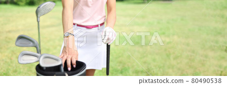 Female golfer stands next to golf bag 80490538